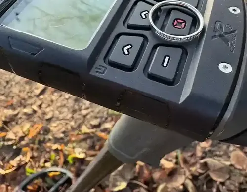 Wiedergefundener goldener Ehering auf der Spule des Metalldetektors im Laub – nach elf Jahren im Garten geborgen
